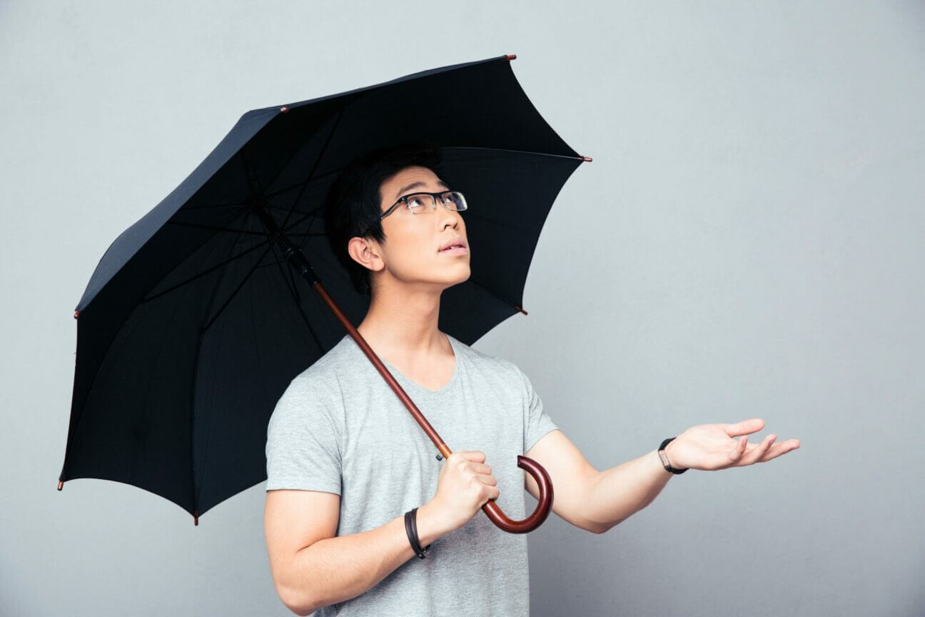 Asian man standing with umbrella